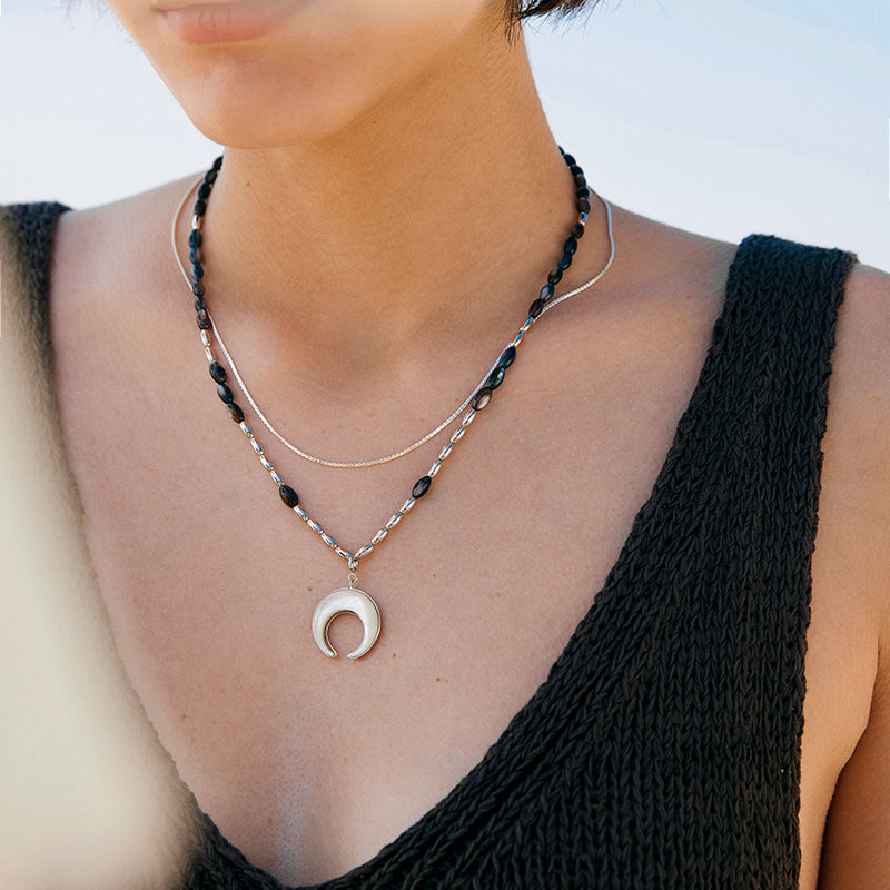 A woman wearing the Double Layer Moon Fritillary Pendant by Maramalive™ on the beach.