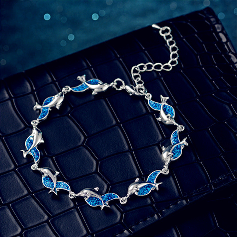 A blue and silver Women's Fashion Dolphin Epoxy Bracelet by Maramalive™ with dolphins on it.