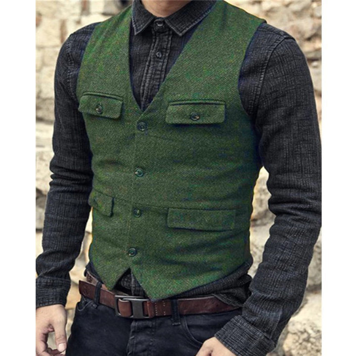 Person wearing a green Maramalive™ European And American Men's Vest Casual Solid Color Herringbone Vest over a dark shirt, paired with black jeans and a brown belt. The outfit, made from a comfortable cotton blend, exudes British style against the stone wall backdrop.