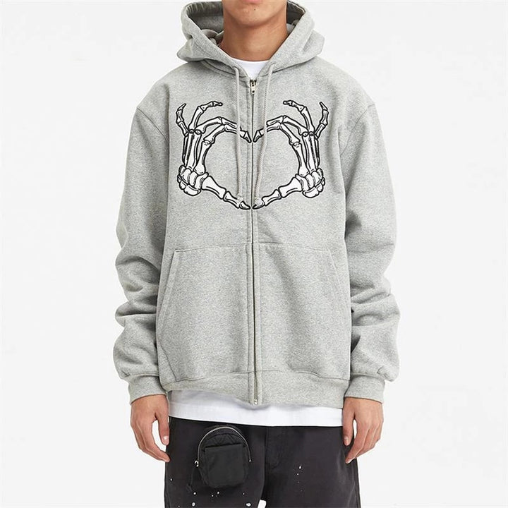 A person wearing a gray Maramalive™ Comfy Zipper Hoodies for Fall: Hooded Sweatshirts & Sweaters with a graphic of skeleton hands forming a heart on the front, white undershirt, black pants, and a small black pouch attached to the waist—perfect as an autumn companion.