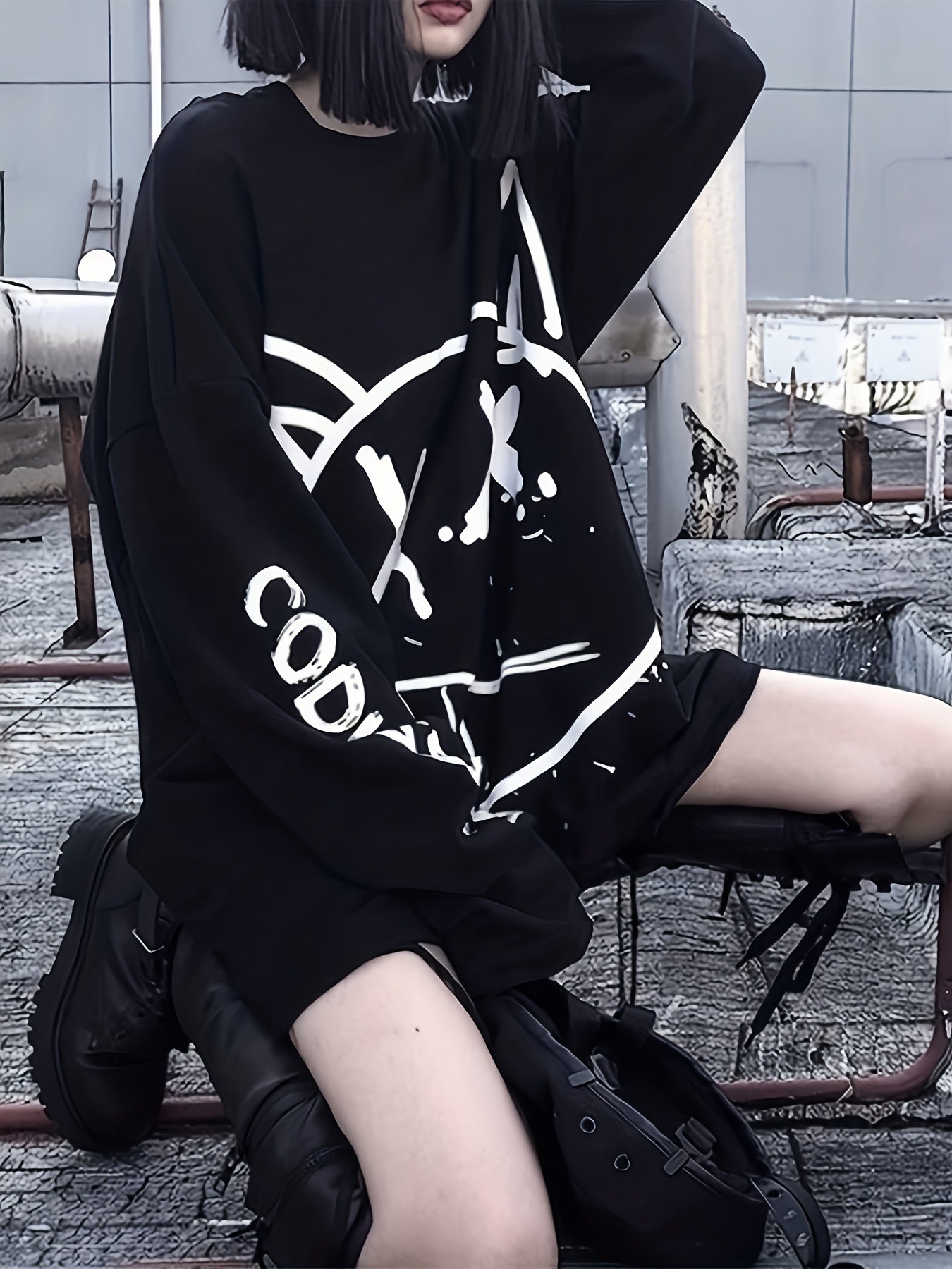 Person with black hair wearing an oversized Maramalive™ Graffiti Print Crew Neck T-Shirt, Casual Loose Long Sleeve Top For Spring & Fall, Women's Clothing and black boots, sitting on an industrial rooftop, radiating Y2K style.