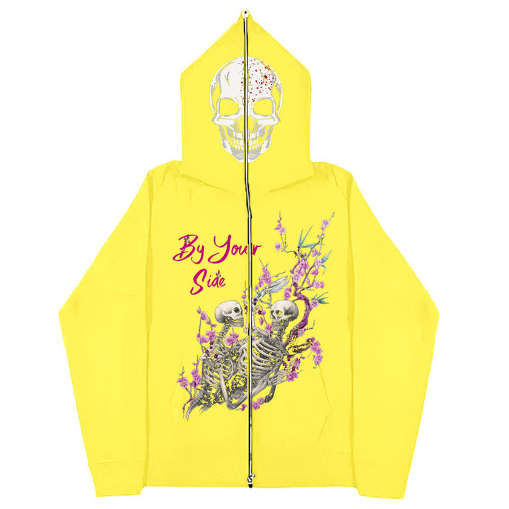 A bright yellow, gothic style hoodie featuring a large skull design on the hood. On the back, two skeletons surrounded by flowers and the text "By Your Side" are displayed. Introducing the Gothic Zipper Sweater: The Perfect Gothic Top Multi-colors by Maramalive™.