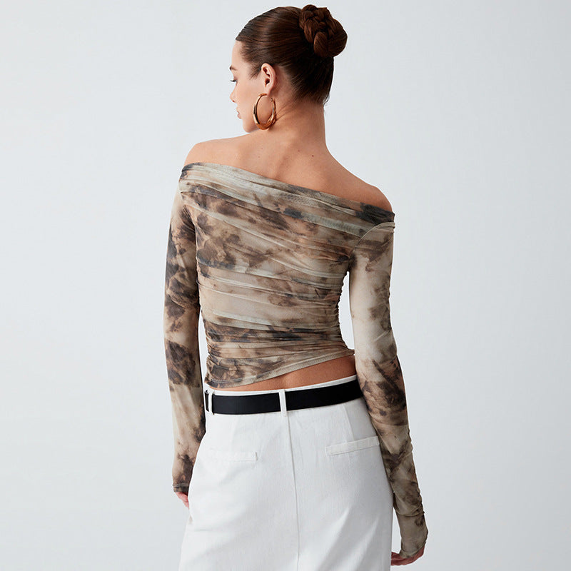 A person with hair in a bun, large hoop earrings, and an off-the-shoulder, long-sleeve tie-dye pullover is shown from the back. They are also wearing white pants with a black belt. The pullover is actually the Printed Off-neck Long Sleeve Backless Pleated Top by Maramalive™.