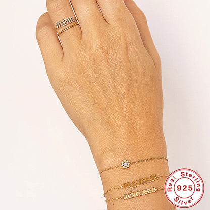 A woman's hand with a Silver Letter Bracelet by Maramalive™ and a ring on it.