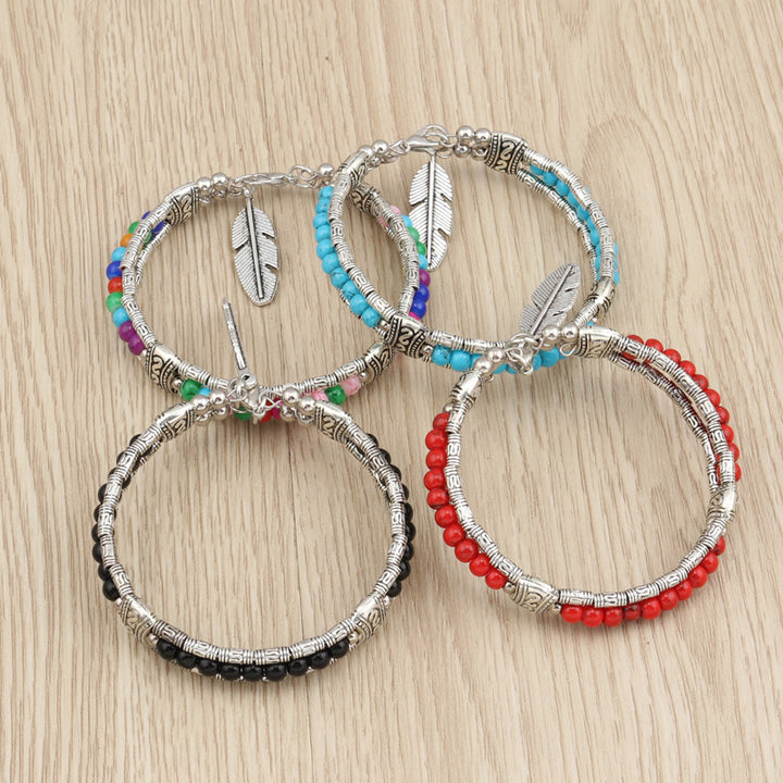 Four Maramalive™ Boho Charm Bracelets made with Alloy Turquoise and alloy Feather Bracelets on a wooden table.