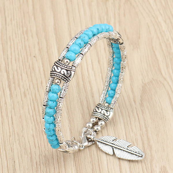 Four Maramalive™ Boho Charm Bracelets made with Alloy Turquoise and alloy Feather Bracelets on a wooden table.