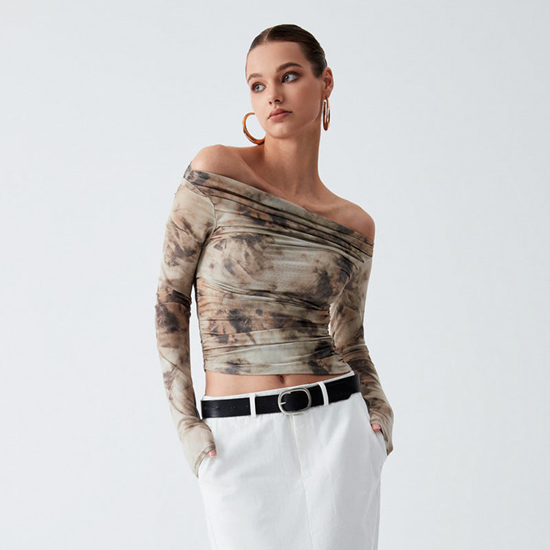 A person stands with hands in the pockets of khaki white pants, wearing a Maramalive™ Printed Off-neck Long Sleeve Backless Pleated Top and large hoop earrings, looking to the side against a plain background.