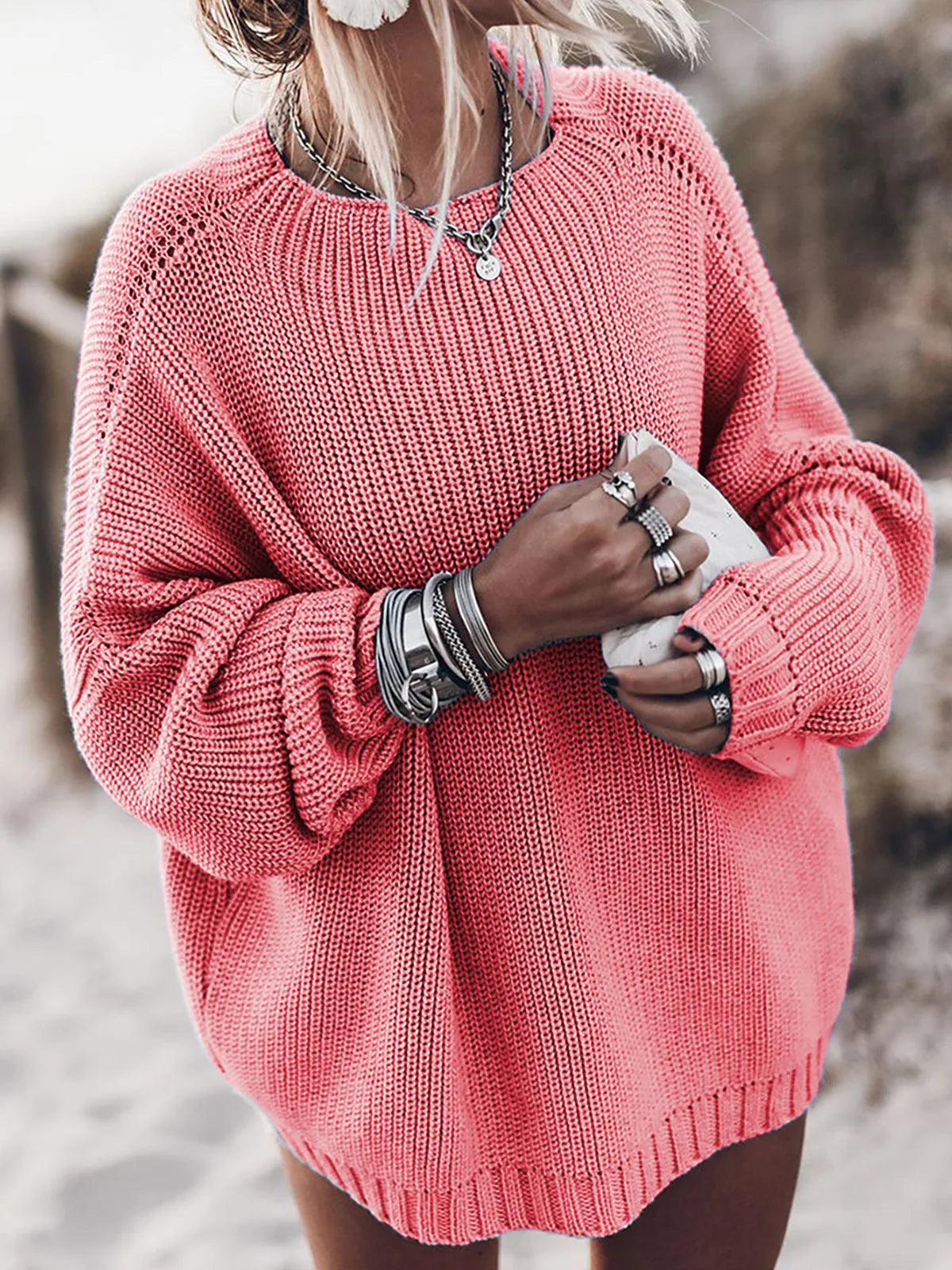 A person wearing a Maramalive™ oversized sweater fall 2022 sweater for women Solid pink blue khaki purple pullover Long sleeve loose knitted sweater, multiple rings, and bracelets is standing outdoors holding a piece of fabric, showcasing stylish women's casual clothing perfect for autumn/winter fashion.