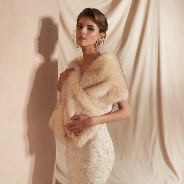 A woman wearing a white lace dress and a Maramalive™ 30 colors Women Fur Capes Champagne Wedding Bolero Faux Fur Stole Bridal Jacket Formal Party Shrug Walk Beside You De Mariage poses elegantly against a beige curtain backdrop.