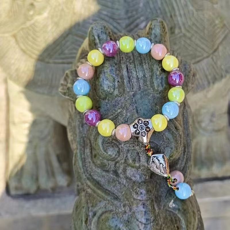 A Maramalive™ Couple's Ceramic Lucky Charm Bead Bracelet Ornament on top of a statue.