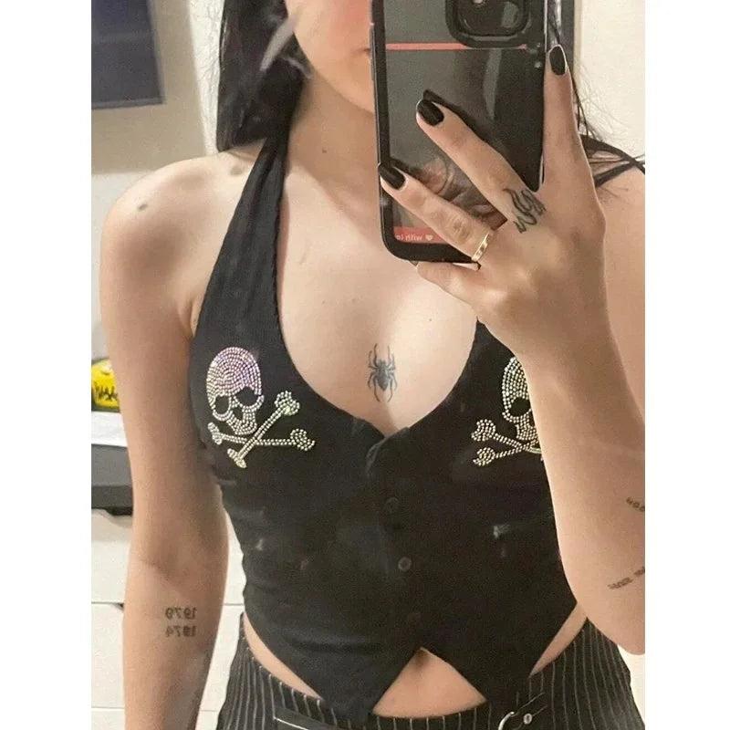 A person with long dark hair takes a mirror selfie, wearing a black Maramalive™ Goth Dark Skull Rhinestone Mall Gothic Halter Tops Grunge Aesthetic Button Up Emo Crop Top Punk Sexy Backless Bandage Alt Outfit and black pants with white stripes. Their nails are painted black, and they have tattoos on their fingers and forearm.