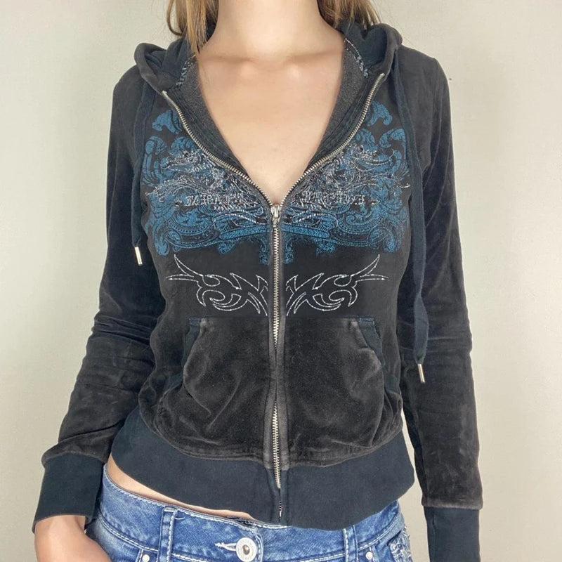 A person wearing a dark, Maramalive™ Y2K Aesthetic Vintage Slim Sweatshirts Embroidery Graphic Pattern Zip Up Hoodies 2000s Retro Grunge Mall Goth Jacket Autumn Coat with blue embroidery and blue jeans. The hoodie has a front pocket and a design featuring abstract patterns and text. The background is plain and light-colored.