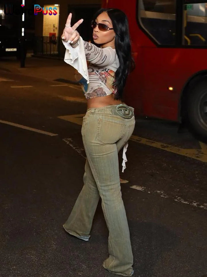 A woman wearing sunglasses, a Maramalive™ One Shoulder Crop Tops Women See Through Biased Collar Bandage Graphics t-Shirt Sexy Clubwear 2024 Summer Thin Tees, and high-stretch flared jeans poses with a peace sign on a city street at night. A red bus is visible in the background.