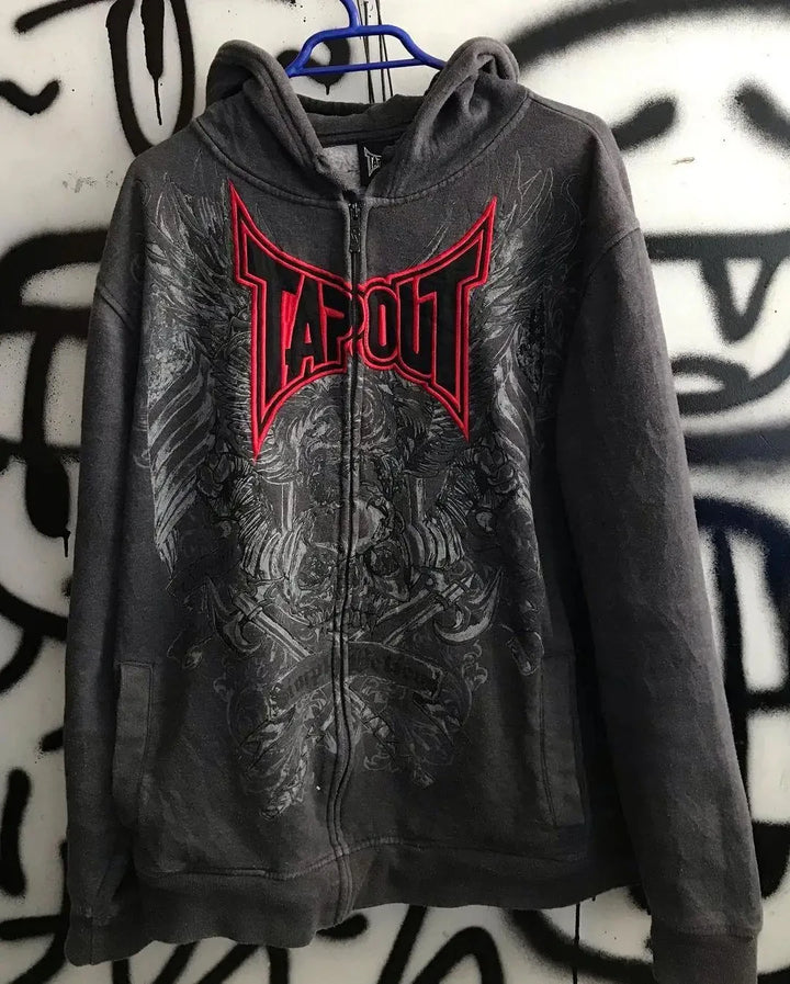 A dark grey zip-up hoodie with a "Maramalive™" logo in red, featuring intricate skull pattern designs on the front, hangs on a blue hanger in front of a graffiti-covered wall. The product is called Gothic Skull Pattern Zip Up Hoodies Men Y2K Embroidery Hip Hop Long Sleeve Loose Hooded Streetwear Sweatshirt Casual Vintage New.