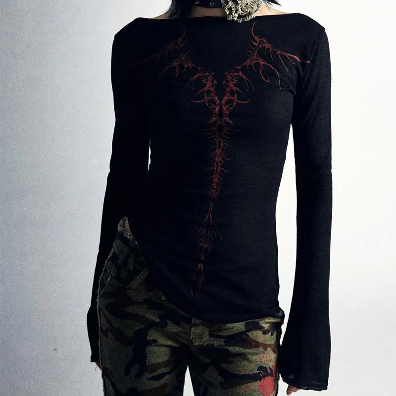 Person wearing a Maramalive™ 90s Vintage E-girl Emo Clothes Fires Graphic Print Y2K Grunge T-shirt Women Retro Long Sleeve Tee Goth Punk Streetwear with camouflage pants, photographed from neck to hips against a plain background.