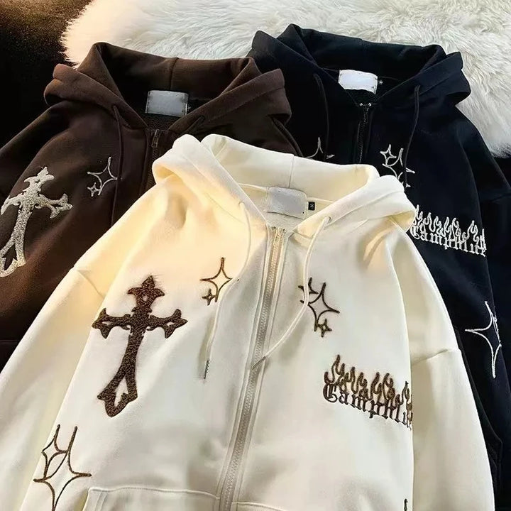 Three Maramalive™ Goth Embroidery Hoodies Women High Street Retro Hip Hop Zip Up Hoodie Loose Casual Sweatshirt Hoodie Clothes Y2k Tops in black, brown, and white with embellished designs including crosses, stars, and flames are laid out on a white fur surface.