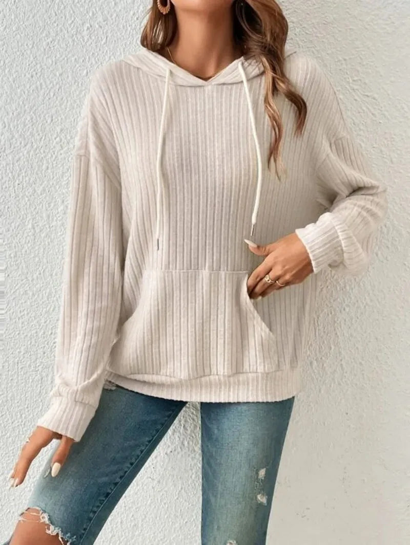 A woman wearing a ribbed, beige Maramalive™ Ladies Casual Knit Hoodie Sweatshirt Fall Winter Y2K Fashion Long Sleeve Women's Loose Hooded Sweater with a front pocket and drawstrings pairs it with light-washed, ripped jeans, epitomizing Fall Winter Fashion.