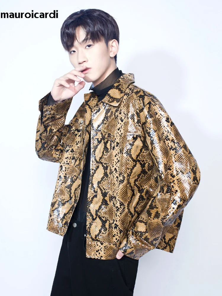 A young person wearing a Loose Cool Shiny Colorful Snakeskin Print Pu Leather Jacket Men Luxury Designer Clothes Streetwear over a black turtleneck poses with one hand near their face against a plain background. Text in the top left corner reads "mauroicardi". This epitomizes youthful casual style in men's outerwear.