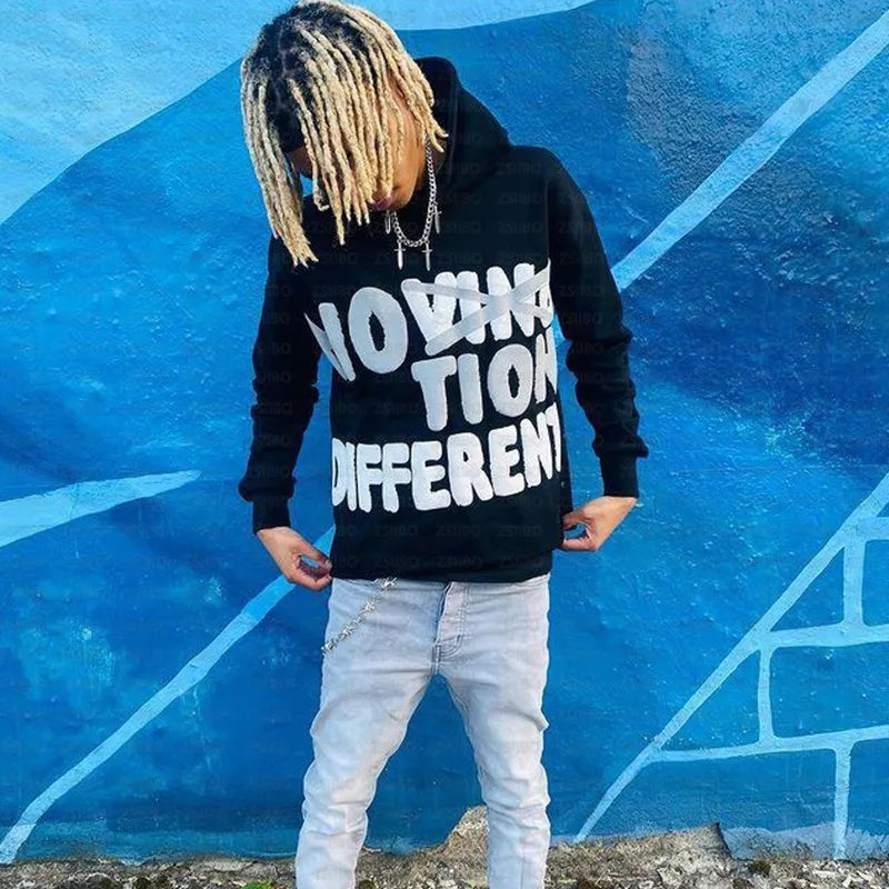 Person with blonde dreadlocks wearing a black Maramalive™ High Street Y2K Hoodie Women Gothic 90s Print Hoodie Kpop Streetwear Sweatshirt Vintage Clothing Punk Loose Hip Hop Jacket Top and light blue jeans, standing against a blue graffiti wall—perfect for showcasing Autumn/Winter fashion trends.