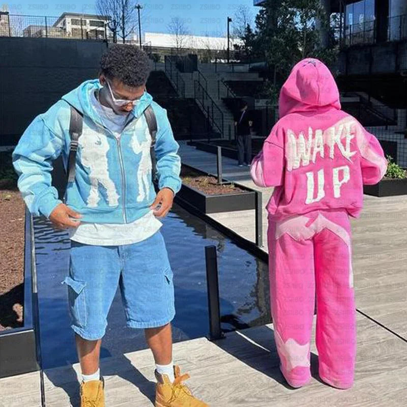 Two people in colorful outfits stand outdoors. The person on the left wears a blue casual sweatshirt and shorts, while the person on the right showcases autumn fashion with a pink Maramalive™ Y2k American High Street Trend Jacket Men Creative Embroidered Zipper Hoodie Harajuku Fashion Retro Oversized Sweatshirt Women and pants that have "WAKE UP" written on the back.