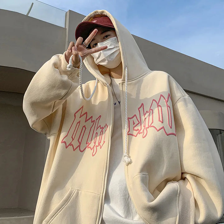 Person wearing a beige Maramalive™ Autumn Men's Letter Foam Print Zip up Hoodies Y2K Goth Streetwear Loose Sweatshirts Female Hip Hop Oversized Hoodie Tracksuit, a red cap, and a white face mask, poses outdoors with a peace sign gesture.