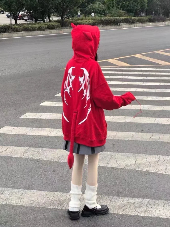 A person wearing a Maramalive™ Gothic Zip Up Hoodies Women Mall Goth Tops Streetwear Kawaii Hooded Sweatshirt 2022 Autumn Pullovers with wing and tail designs stands at a crosswalk, facing away from the camera.