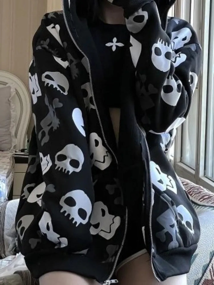 Person wearing a Maramalive™ Gothic Punk Skull Hoodies Women Mall Goth Tops Streetwear Black Long Sleeve Zip Up Hooded Sweatshirt 2022 Autumn, unzipped to reveal a black top underneath. This streetwear look captures the essence of Autumn 2022. The background shows a bed and a window.