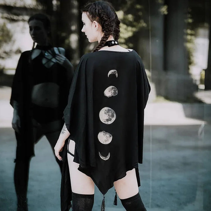 A person with braided hair stands in front of a reflective surface, wearing the Maramalive™ Gothic Black Retro Moon Print Tassel Cloak Female Autumn and Winter Dark V-neck Loose Top Bat Cloak Goth Jacket Women, exuding a distinct gothic style.