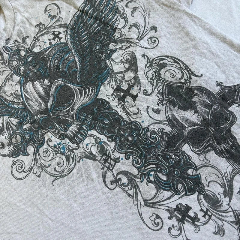 A graphic design on a light-colored fabric featuring illustrative skulls, intricate swirls, and floral elements in dark teal and black tones, reminiscent of Maramalive™ 2000s Retro Grunge T-shirts Women Y2K Cyber Goth Emo Skull Tees E-girl Graphic Print Short Sleeve Tops Vintage Streetwear.