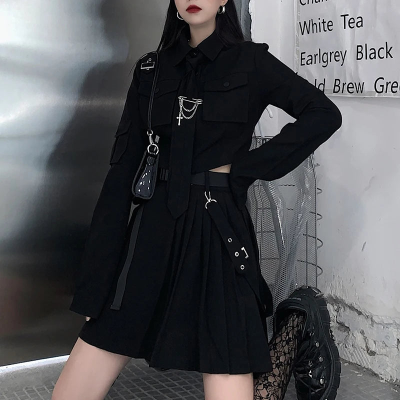 Person dressed in Maramalive™ EMO Gothic Cargo Shirt Suit Egirl Punk Chain Ribbon Skirts Goth Dress Autumn Streetwear Black Grunge Aesthetic Clothes, standing with one hand on their hip. The wall nearby has a sign listing different food and beverage items.