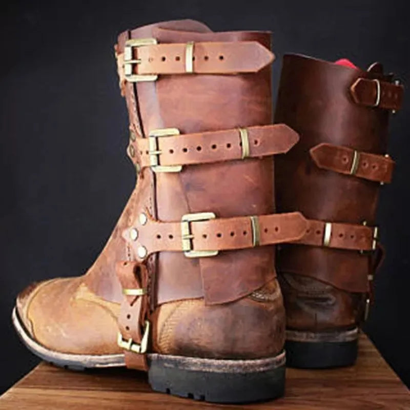 A pair of worn brown leather boots with multiple buckles and straps, placed on a wooden surface against a dark background evoke the aura of historical costumes. Instead, imagine the 1 Pair Medieval Knight Warrior Gaiters Armor Leather Boot Shoes Cover Waterproof Leg Guards Renaissance Costume Accessory Larp by Maramalive™ in their place to truly capture that timeless essence.