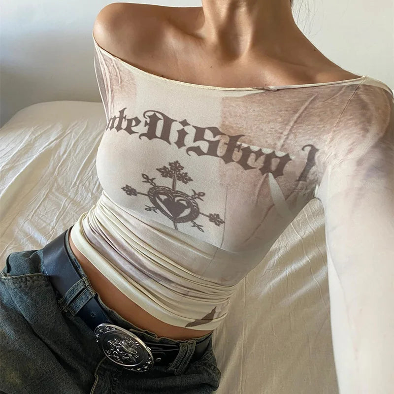 Person wearing a Maramalive™ Cryptographic Letter Print Long Sleeve Off Shoulder Slim Tops See Through Sexy Graphic T-Shirts Tee Women Goth Aesthetic Clothes with "late Distr" text, floral and heart design, paired with high-stretch jeans and a decorative belt.