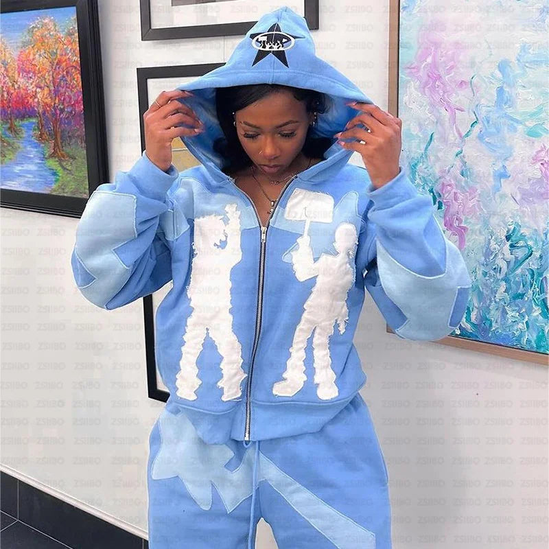 A person wearing a light blue Maramalive™ Y2k American High Street Trend Jacket Men Creative Embroidered Zipper Hoodie Harajuku Fashion Retro Oversized Sweatshirt Women and sweatpants with white silhouette designs stands in front of colorful paintings, adjusting the hood.
