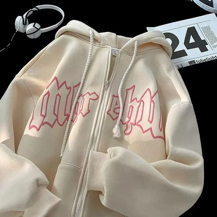 A cream-colored Maramalive™ Autumn Men's Letter Foam Print Zip up Hoodies Y2K Goth Streetwear Loose Sweatshirts Female Hip Hop Oversized Hoodie Tracksuit with a front zipper and pink Gothic lettering on the front is displayed on a black surface with a set of white headphones and a calendar.