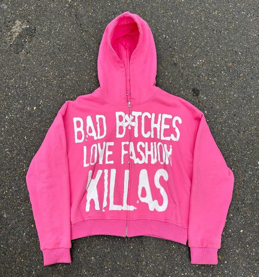 A Maramalive™ y2k Streetwear Goth Letter Print Oversized Hoodie Women 2024 Fashion Casual Loose Harajuku Versatile Zipper Sweatshirt Top with a front zipper, featuring a slogan in white text that reads "BAD B*TCHES LOVE FASHION KILLAS." The loose-fit hoodie is laid flat on an asphalt surface.