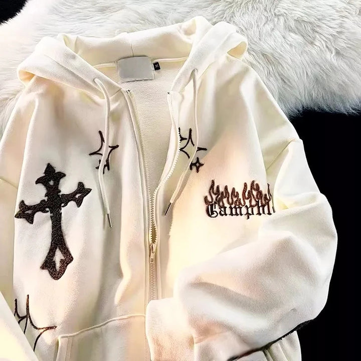 A Maramalive™ Goth Embroidery Hoodies Women High Street Retro Hip Hop Zip Up Hoodie Loose Casual Sweatshirt Hoodie Clothes Y2k Tops with black cross, star, and flame designs on the front is laid out on a furry white surface. Perfect for women's fashion enthusiasts who love edgy streetwear styles.