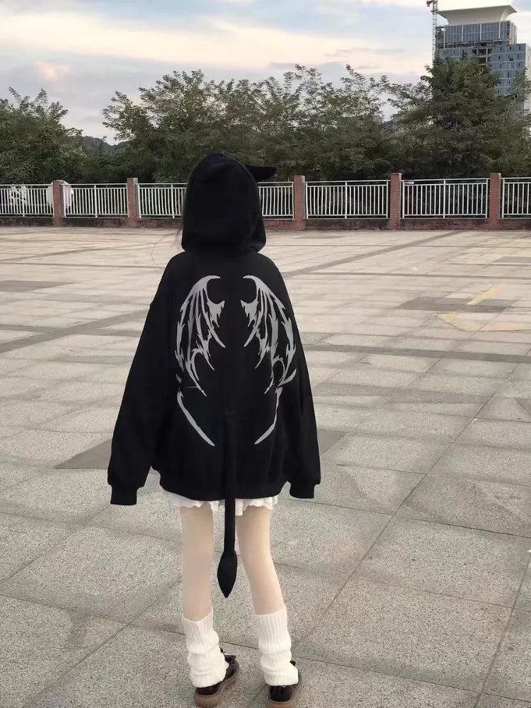 A person wearing a black hoodie with wing-like designs and a tail stands on a paved area, framed by trees and a fence. This Maramalive™ Gothic Zip Up Hoodies Women Mall Goth Tops Streetwear Kawaii Hooded Sweatshirt 2022 Autumn Pullovers effortlessly blends comfort and edgy flair, making it a standout in women's fashion.