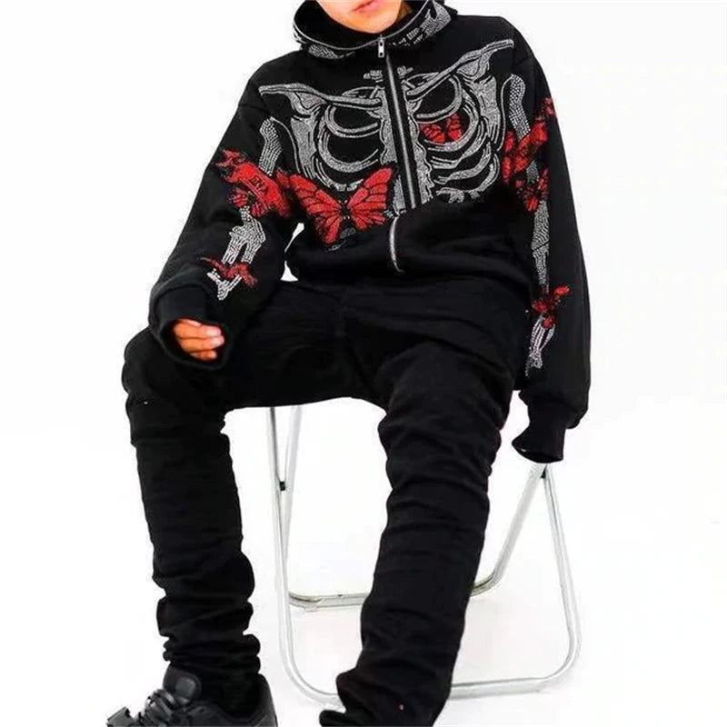 Person dressed in black pants and a punk style black hoodie with a skeleton and red butterfly design, seated on a white folding chair against a plain background. Perfect for those who love the Maramalive™ Goth Clothing Rhinestones Skeleton jacket Hoodies Punk Long Sleeve Streetwear Oversized Zip Men Y2K Casual Hoodie Sweatshirt New that make a statement, suitable for both spring and autumn.
