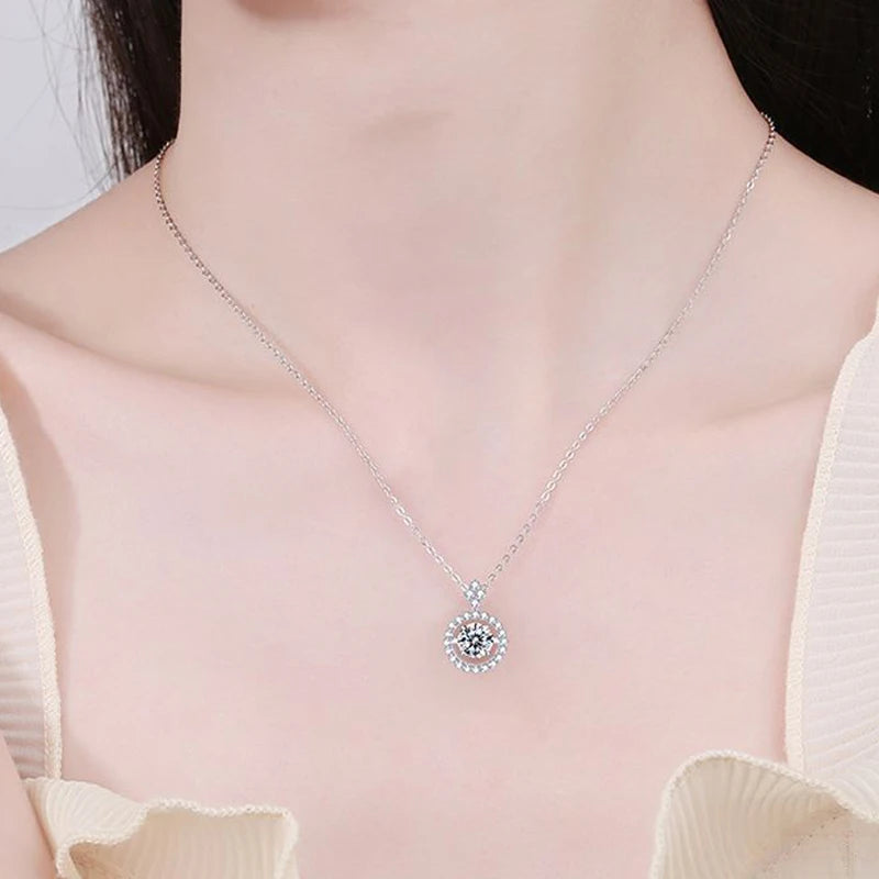 A person wearing a Maramalive™ 1/0.8 CT Moissanite Pendant For Women Simulated Diamond Necklace S925 Sterling Silver Jewelry Girl Valentine's Day Gift featuring a dark center and surrounded by lighter stones.