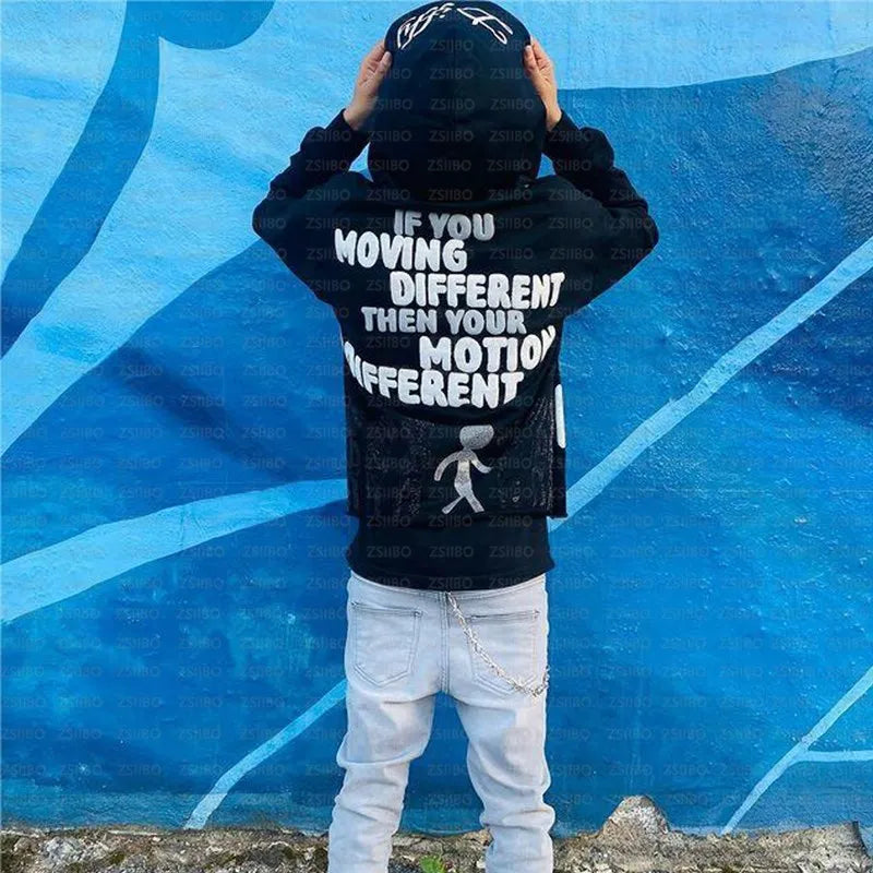 A person in a black Maramalive™ High Street Y2K Hoodie Women Gothic 90s Print Hoodie Kpop Streetwear Sweatshirt Vintage Clothing Punk Loose Hip Hop Jacket Top and light jeans stands with their back to the camera, facing a blue mural. The hoodie reads, "If you moving different then your motion different." Perfect for those seeking autumn/winter fashion staples.