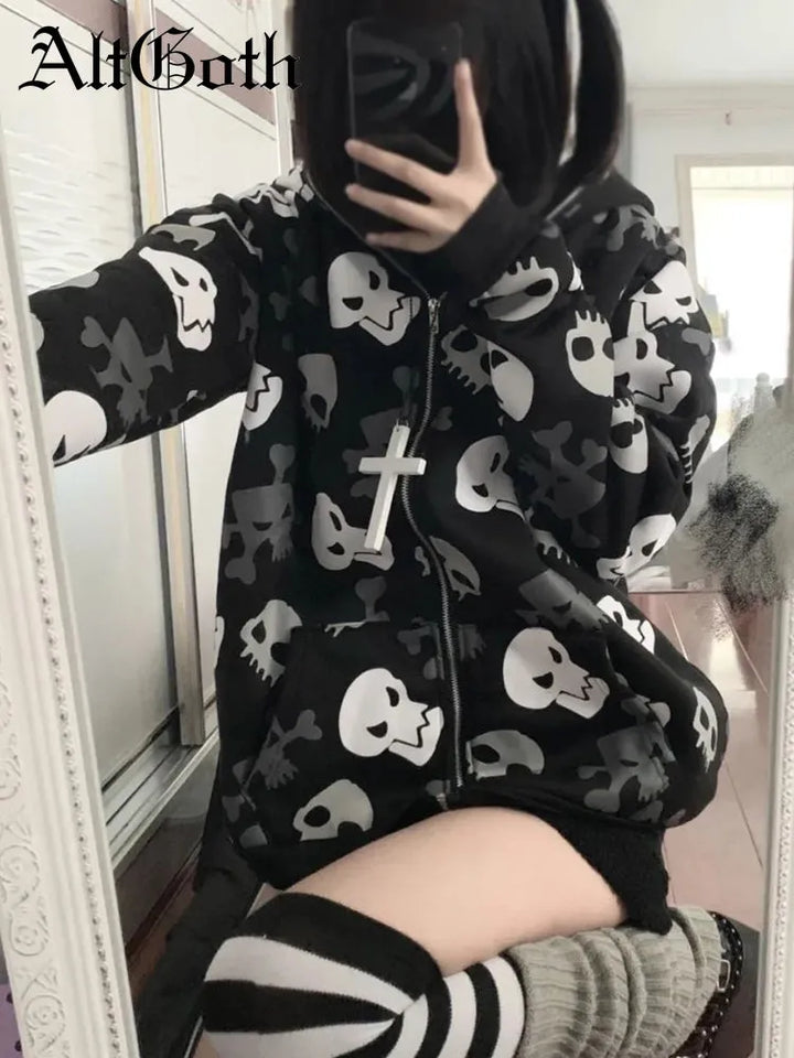 Person wearing a black Maramalive™ Cyberpunk Y2k Sweatshirt Women Mall Goth Skull Printed Long Sleeve Zipper Cardigan Hoodie Emo Alt Indie Clothes with white skull designs, striped socks, and a large cross necklace, taking a mirror selfie. The room is bright with a reflective surface nearby.