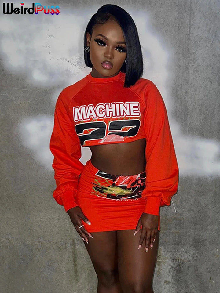Person posing against a gray background, wearing a red outfit with "MACHINE 22" on the top. The ensemble's casual dress style is elevated by its elastic waist, blending both comfort and fashion effortlessly. They are dressed in the Maramalive™ Letter Hipster 2 Piece Set Women Sporty Casual Skinny Lantern Sleeve Crop Tops+Skirts Trend Streetwear Matching Suits.
