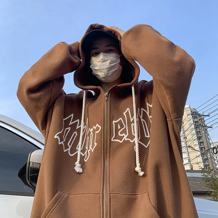 Person in a Maramalive™ Autumn Men's Letter Foam Print Zip up Hoodies Y2K Goth Streetwear Loose Sweatshirts Female Hip Hop Oversized Hoodie Tracksuit adjusts their hood while wearing a face mask, standing outside near a white vehicle and building.