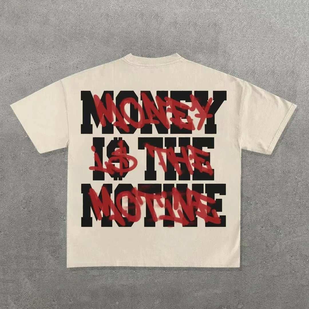 A beige Punk Hip Hop Graphic T Shirts Mens Vintage Y2k Top Goth Oversized T Shirt Fashion Loose Casual Short Sleeve Streetwear from Maramalive™ with bold black text saying "MONEY IS THE MOTIVE," partially obscured by red graffiti-style text that reads "MONEY." The shirt is laid flat on a gray surface.
