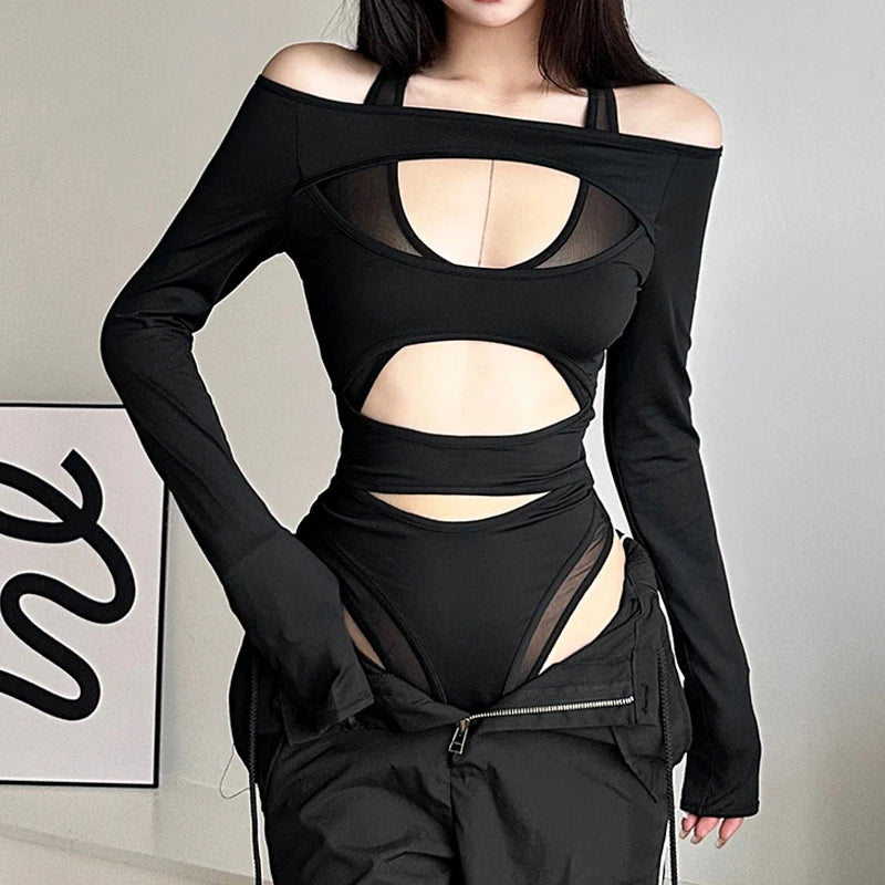 A person wearing a Maramalive™ Goth Dark Cyber Y2k Punk Hollow Out Sexy Bodysuits Mall Gothic Bodycon Mesh Sheer T-shirts Women Long Sleeve Patchwork Bodysuit, featuring punk hollow out details, long sleeves, and a high-waisted design stands indoors. Their face is not visible.