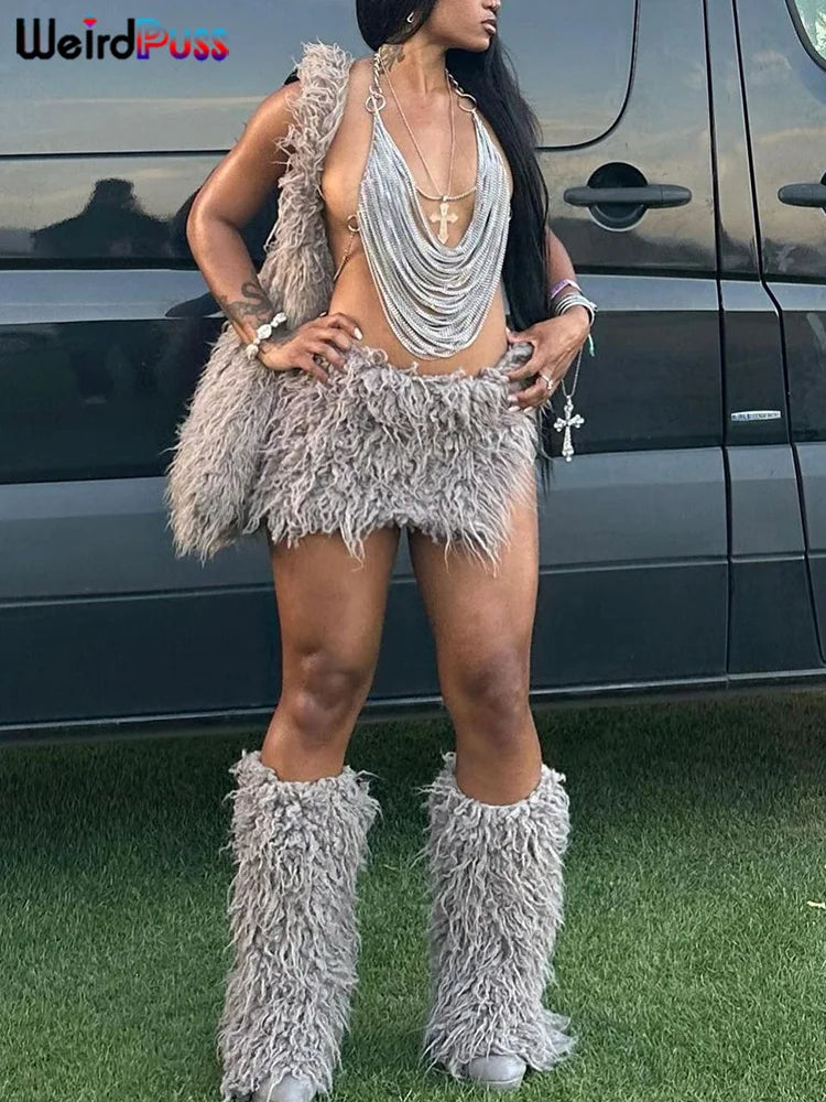 A person stands in front of a vehicle, wearing a grey, fluffy outfit consisting of a Multilayer Chain Women Crop Tops Halter Backless Low Chest Sexy Fashion Hot Girls Rave Party Nightclub Coquette Vest by Maramalive™, skirt, and boots, along with layered necklaces and bracelets—perfect for adding an edgy twist to your summer look.