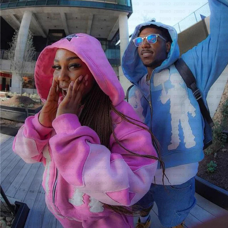 Two people showcasing vibrant autumn fashion stand side by side. The person on the left sports a pink women's Maramalive™ Y2k American High Street Trend Jacket Men Creative Embroidered Zipper Hoodie Harajuku Fashion Retro Oversized Sweatshirt Women adorned with white designs, while the person on the right rocks a blue casual sweatshirt paired with matching shorts and stylish sunglasses.