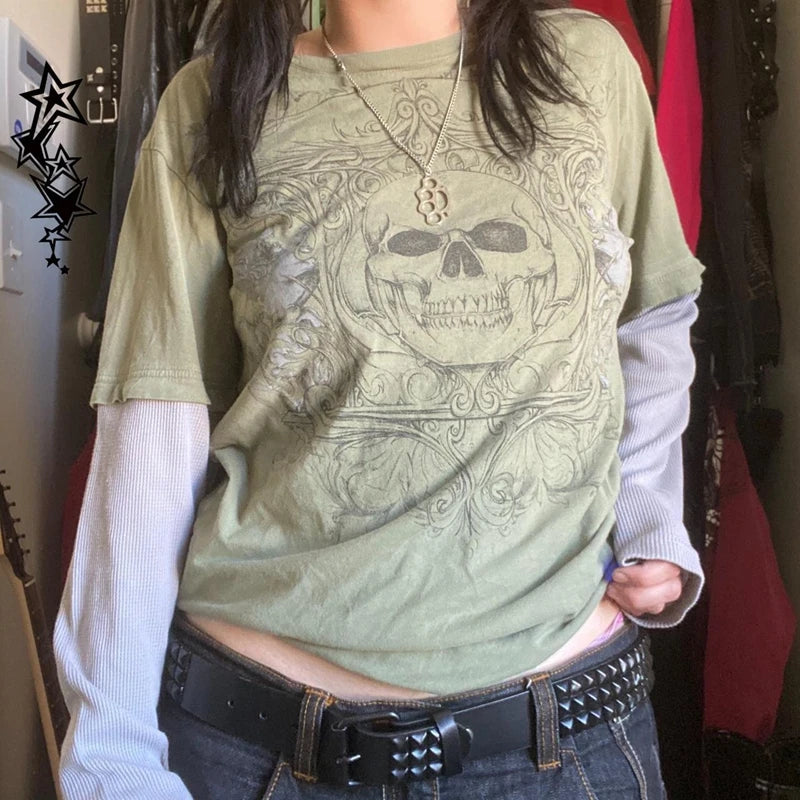 Person wearing a Maramalive™ 2000s Retro Mall Goth Graphic Print Loose Tops Cyber Y2K Grunge Vintage Oversize T-shirt Fake 2 Piece Patchwork Long Sleeve Tees with a skull design, and a black studded belt, embracing Y2K style. Background includes some hanging clothes.