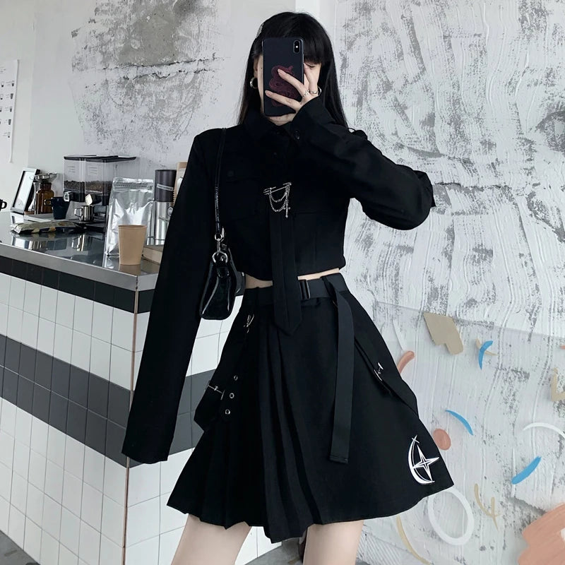 A person dressed in black emo clothing women is taking a mirror selfie in a modern, minimalistic setting. The wall behind them is white with abstract gray and black details. They are wearing the EMO Gothic Cargo Shirt Suit Egirl Punk Chain Ribbon Skirts Goth Dress Autumn Streetwear Black Grunge Aesthetic Clothes by Maramalive™.