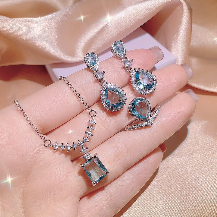 A Women's Inlaid Blue Zircon Ring Earrings Necklace set on a satin from Maramalive™.